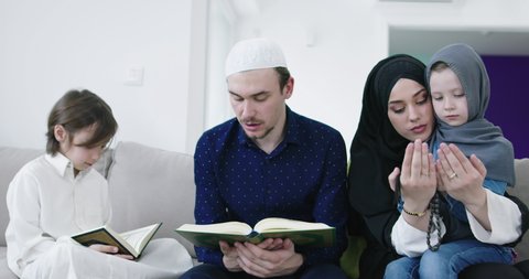 Muslim family reading Quran and praying together on the sofa