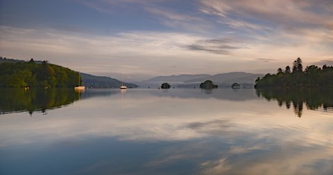 Lake District sunrise landscape time lapse at Lake Windermere. 4k timelapse of perfect reflection of sailing boats and beautiful cloudsing in Cumbria, England in typical relaxing British scenery