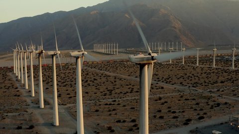 Cinematic aerial of field with windmills at sunset, desert in California, renewable energy