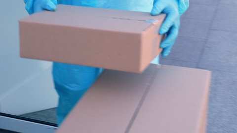 close-up, Delivery of parcels with medical equipment or drugs to hospital during coronavirus outbreak. Courier, in protective suit, is handing cardboard boxes to nurse. Cargo delivery service during