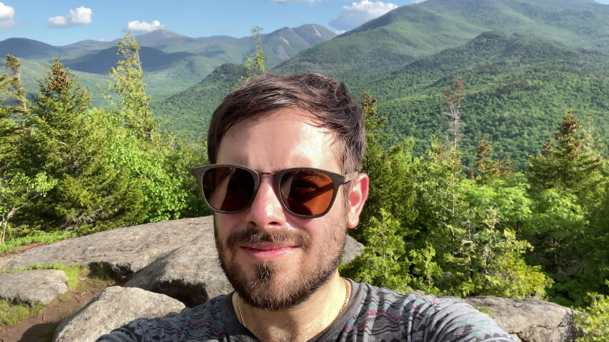 Man spinning around while taking a selfie  during a hike on a mountain