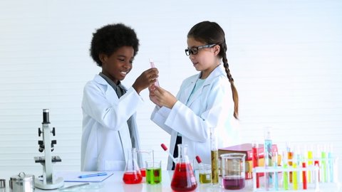 Two kids in lab coat learning chemistry in school laboratory, Kid scientist studying science, experimenting with chemicals, Young scientist making experiments laboratory, Child and science, Education.