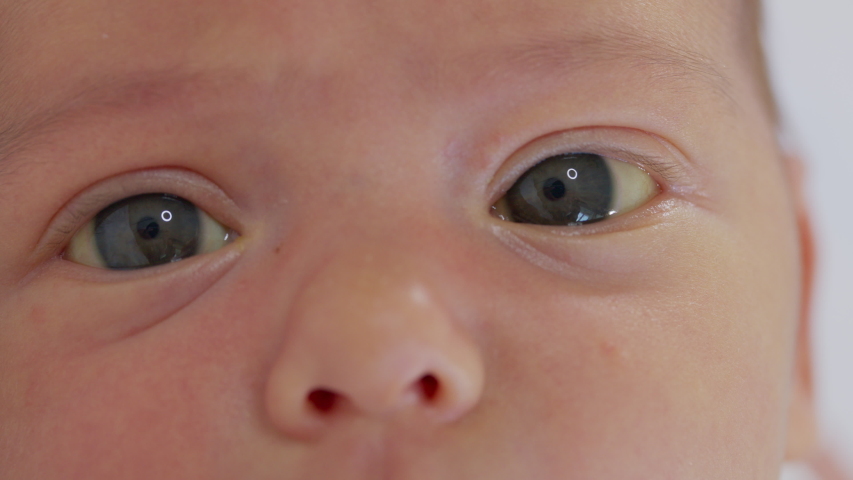 Close-up the face of a newborn baby in the early days who wakes up and opens his eyes. A newborn baby grimaces through a dream. Newborn in the first minutes of life. Royalty-Free Stock Footage #1055922938