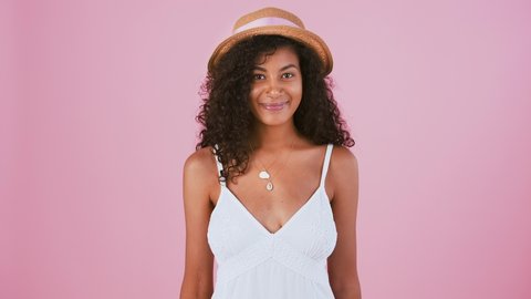 Young afro-american woman smiling and imitating zipping her mouth shut and throwing out the key. Keep a secret. Posing on pink background. Close up