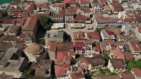 Aerial drone fly through video from medieval old clock tower in Acronafplia castle overlooking historic and picturesque seaside old town of Nafplio, Argolida, Peloponnese, Greece