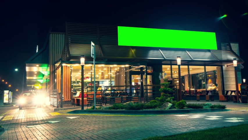 Green screen billboard or wide display on a building of express service cafe. Entertainment, consumerism and chroma concept. Visitors come in and out at. cars drive up for their portion of fast food. | Shutterstock HD Video #1055925353