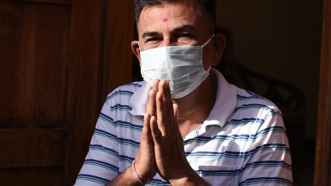 Indian man wearing medical mask doing namaste during the coronavirus pandemic