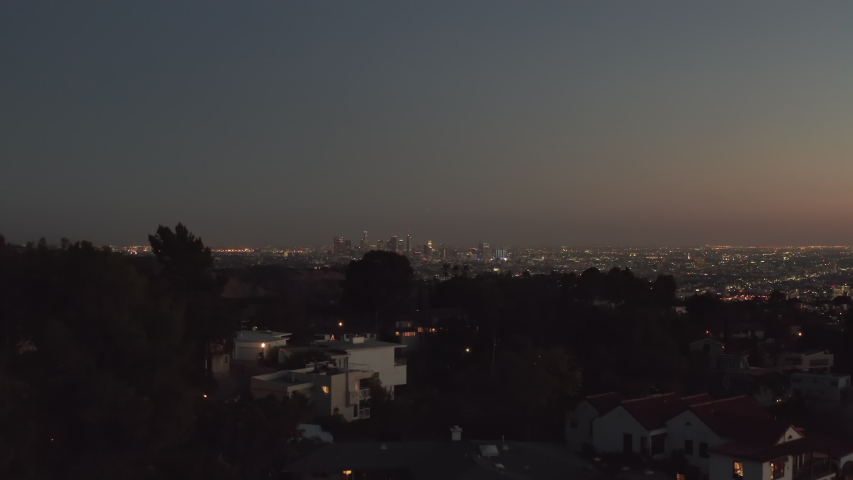 Over Hollywood Hills at Night with view on Downtown Los Angeles Skyline, Aerial Establishing Shot, slow Dolly in forward