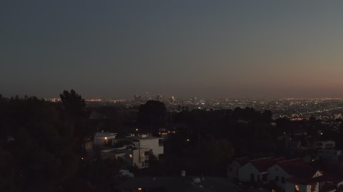 Over Hollywood Hills at Night with view on Downtown Los Angeles Skyline, Aerial Establishing Shot, slow Dolly in forward