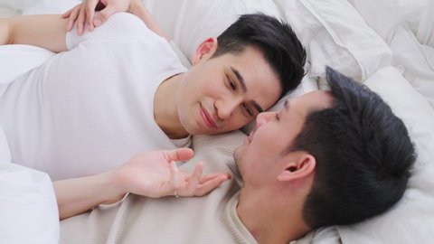 LGBT concept, Asian gay lover, just married homosexual couple lying on bed together in bedroom then bring blanket to cover them. Playing something fun together under blanket. Gay and lesbian concept.