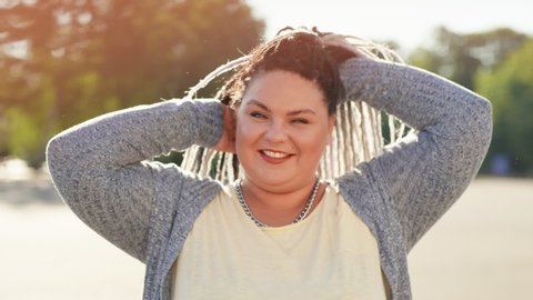 Portrait of happy smiling woman with dreads posing for camera at beautiful sunny summer day. Pretty fat or stout girl showing body positive attitude to herself. Concept of diverse beauty and lifestyle