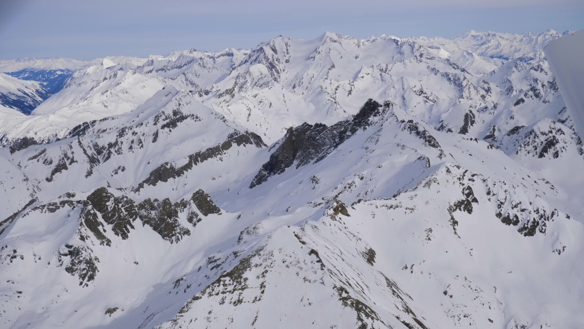 Looking outside plane window at snow covered mountains of heavenly Austrian Alps