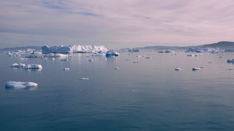 Greenland. Icebergs. Nature and landscapes of Greenland. Disko bay. West Greenland. Summer Midnight Sun and icebergs. Big blue ice in icefjord. Affected by climate change and global warming.
