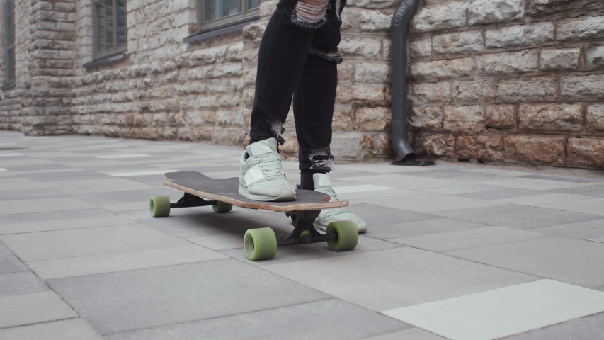 Portrait of stylish teenage young guy riding on the skateboard outdoor. Teenager with a skate board on the street. Sport and subculture.