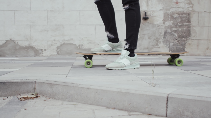 Portrait of stylish teenage young guy riding on the skateboard outdoor. Teenager with a skate board on the street. Sport and subculture.