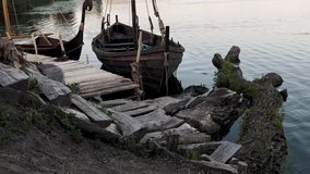 This stock video shows vintage Viking style wooden boats moored on the edge of a lake.