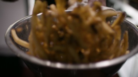 Fresh french fries. Tossing and seasoning some fresh french fries at a restaurant. Professional chef preparing fan favorite. Shot in slow-motion and 4k. 