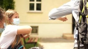 Curly masked schoolboy goes to school. He greets classmates contactlessly with the help of his elbow. Social distance, back to school, new rules - Powered by Shutterstock - Get 15% off with code: PIKWIZARD15