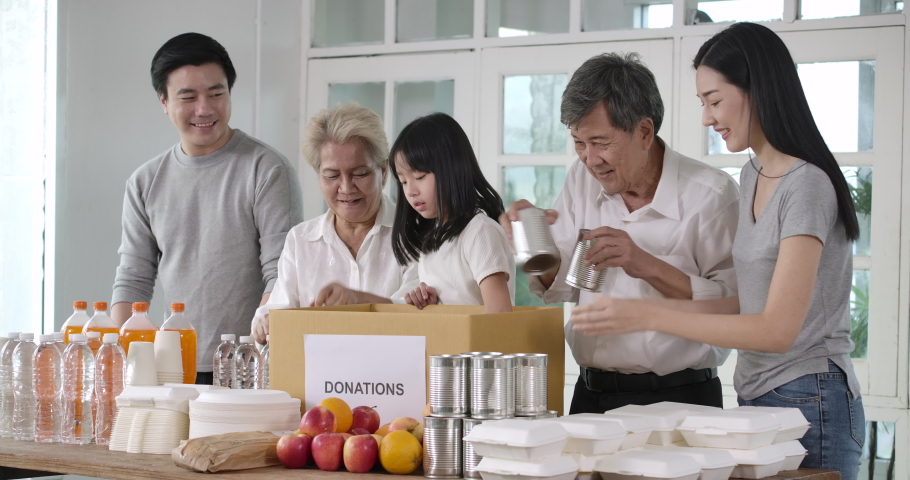 Group of asian volunteers family putting food products in donation box together as charity workers and members of community work to the poor during the Coronavirus pandemic. social distance concept. Royalty-Free Stock Footage #1055951414