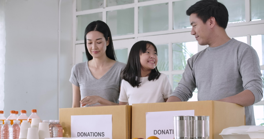 Group of Young asian male and female volunteers family putting food products in donation box together as charity workers and members of the community work to the poor during the Coronavirus pandemic. Royalty-Free Stock Footage #1055951417