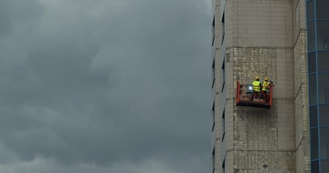Team of windows cleaner outside the windows of sky scraper building. Picture also shows the safety suit and instrument.