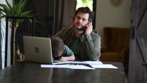 Father is trying to work and play with a little boy at same time at home. 