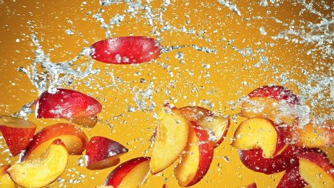 Super Slow Motion Shot of Flying Fresh Peach Slices and Water Side Splash on Yellow Background at 1000fps.