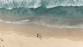Beautiful summer aerial video. Overhead view of people walking by the white sandy beach along the amazing clear light blue ocean. 4K cinematic background footage for commercial use. California, USA