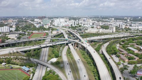 Aerial of rush hour traffic with highway panorama. 4k slow motion transportation and cars above suburban area. Drone flight over multi-level intersection on sunny day. Beautiful Miami city, Florida