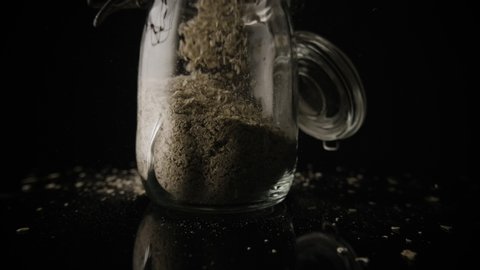 Oats filling up a glass jar on an isolated black background.