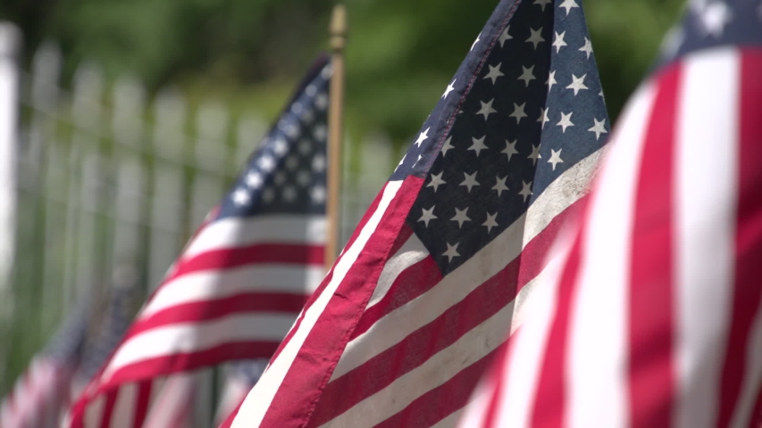 Old Glory American flag waves with white picket fence in background