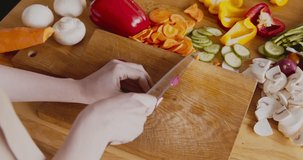 Woman cutting fresh radish on kitchen cutting board, top view