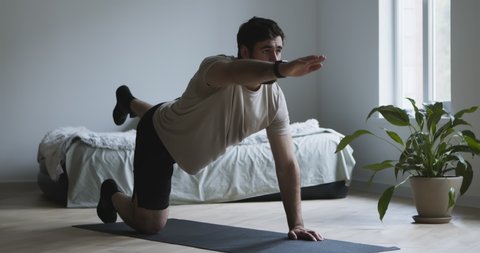 Stretching training. Young man exercising on fitness mat at home