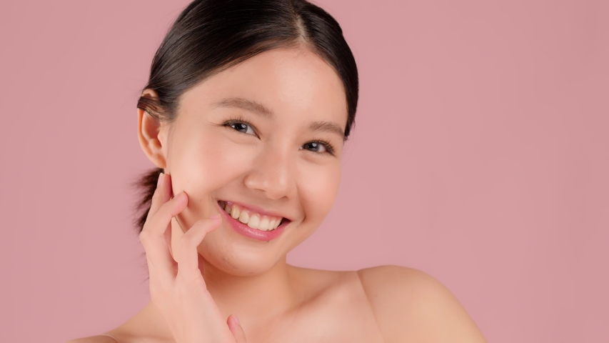 Close up Slow motion Beauty shot of Beautiful Asian girl looking at camera isolated on pink background | Shutterstock HD Video #1055969117