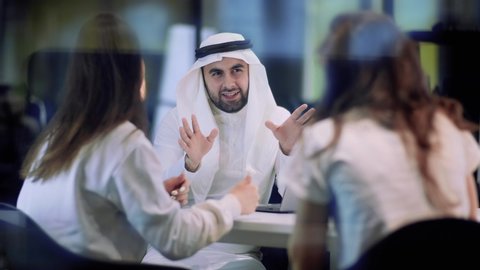 Business people of different nationalities, discussion of finance in a modern negotiation room, business cooperation concept, creative approach, an arab man gesturing with his hands.
