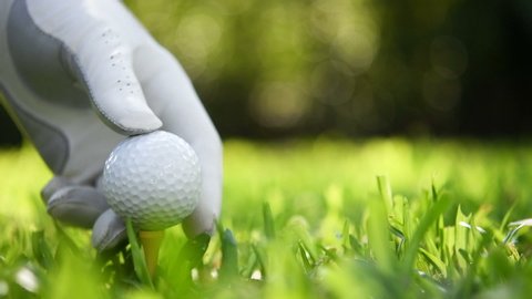 Hand putting golf ball on green grass slow motion.