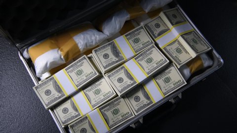 A hand packing narcotic drugs and money in briefcase.