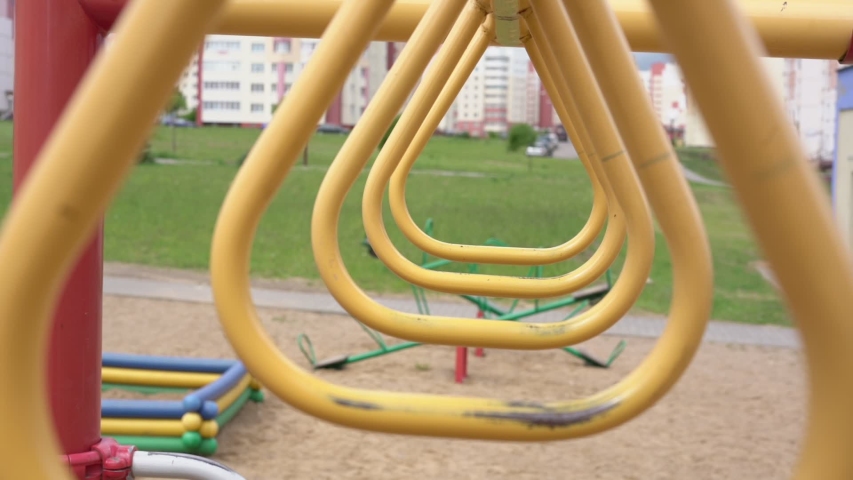 metal attraction of yellow colour located on playground against green meadow and city buildings slow motion close view