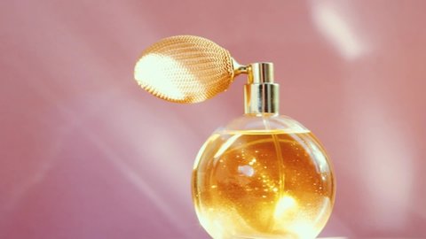 Luxury golden perfume bottle and shining light flares on pink background, glamorous fragrance scent as perfumery product for cosmetic and beauty brand, stock footage