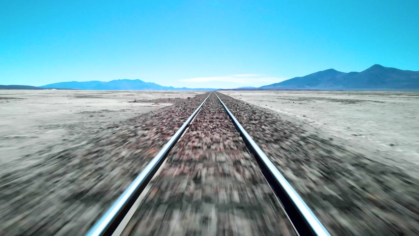 Aerial drone shot speeding along the middle of unused train tracks in Uyuni salt flats in Bolivia