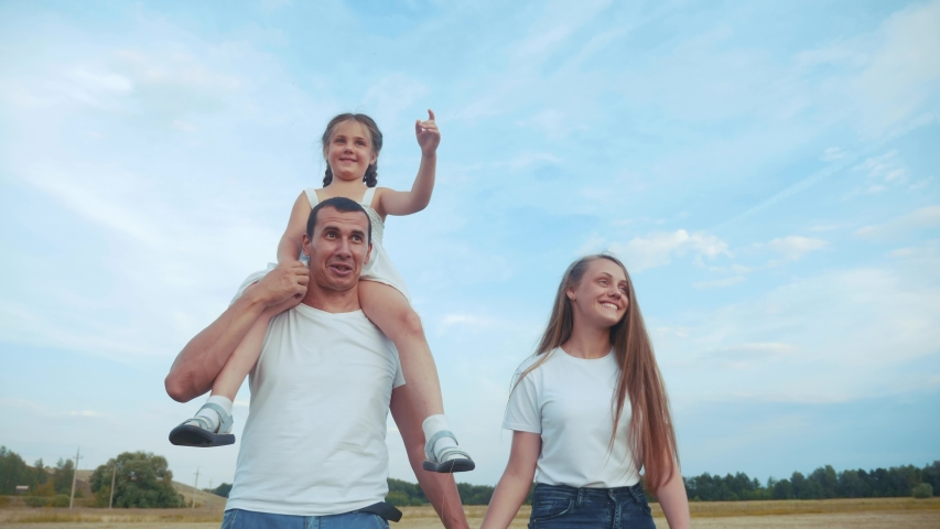 dream holiday concept. happy family fun walks in the park with kid. parent father and mother carry children with sister and daughter on their backs go field. friendly family a walks lifestyle together