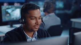 Close Up Portrait of a Joyful Technical Customer Support Specialist Talking on a Headset while Working on a Computer in a Call Center Control Room Filled with Computer Display Screens and Data Servers - Powered by Shutterstock - Get 15% off with code: PIKWIZARD15