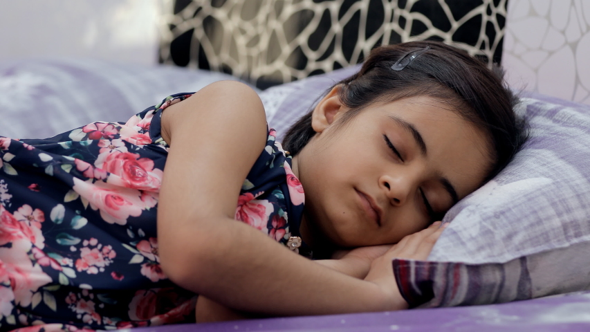 Closeup shot of an adorable Indian girl sleeping comfortably in her bedroom. Portrait of a peaceful little kid/child enjoying good healthy mid-day nap on her soft pillow - lifestyle kids concept
