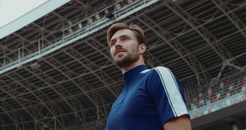 Young adult Caucasian male sportsman soccer player entering and admiring a large empty stadium. Shot on RED Cinema camera