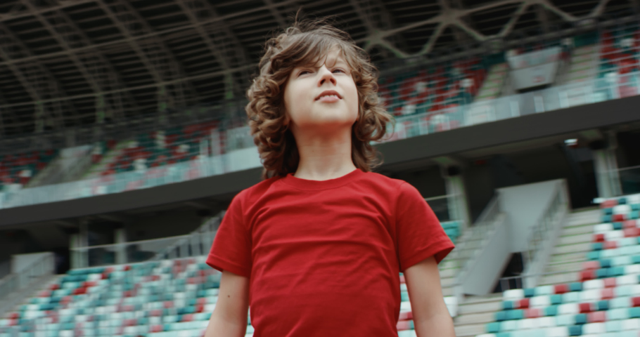 Cute little kid boy soccer player spreading hands on an empty stadium, dreaming of becoming professional player, soccer star. RED cinema camera RAW graded footage | Shutterstock HD Video #1055995286