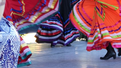 Latino women in colourful traditional dresses dancing Jarabe tapatio, mexican national folk hat dance. Street performance of female hispanic ballet in multi colored ethnic skirts. Girls in costumes.
