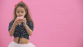Little girl dressed in polka dot eats delicious donuts in 4k video.