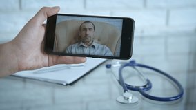 Doctor consults online. A man talking to a doctor by video call on a smartphone.