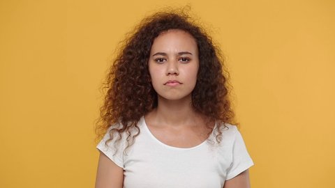 Young tired african american woman 20s years old in white t-shirt posing isolated on yellow background studio. People lifestyle concept. Looking camera yawning want to sleep cover mouth with hand