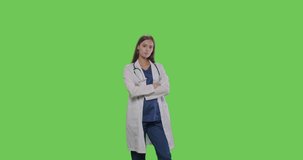 Portrait of female doctor on green screen isolated with chroma key. Woman standing with arms crossed looking at camera smiling. 4K RAW graded footage